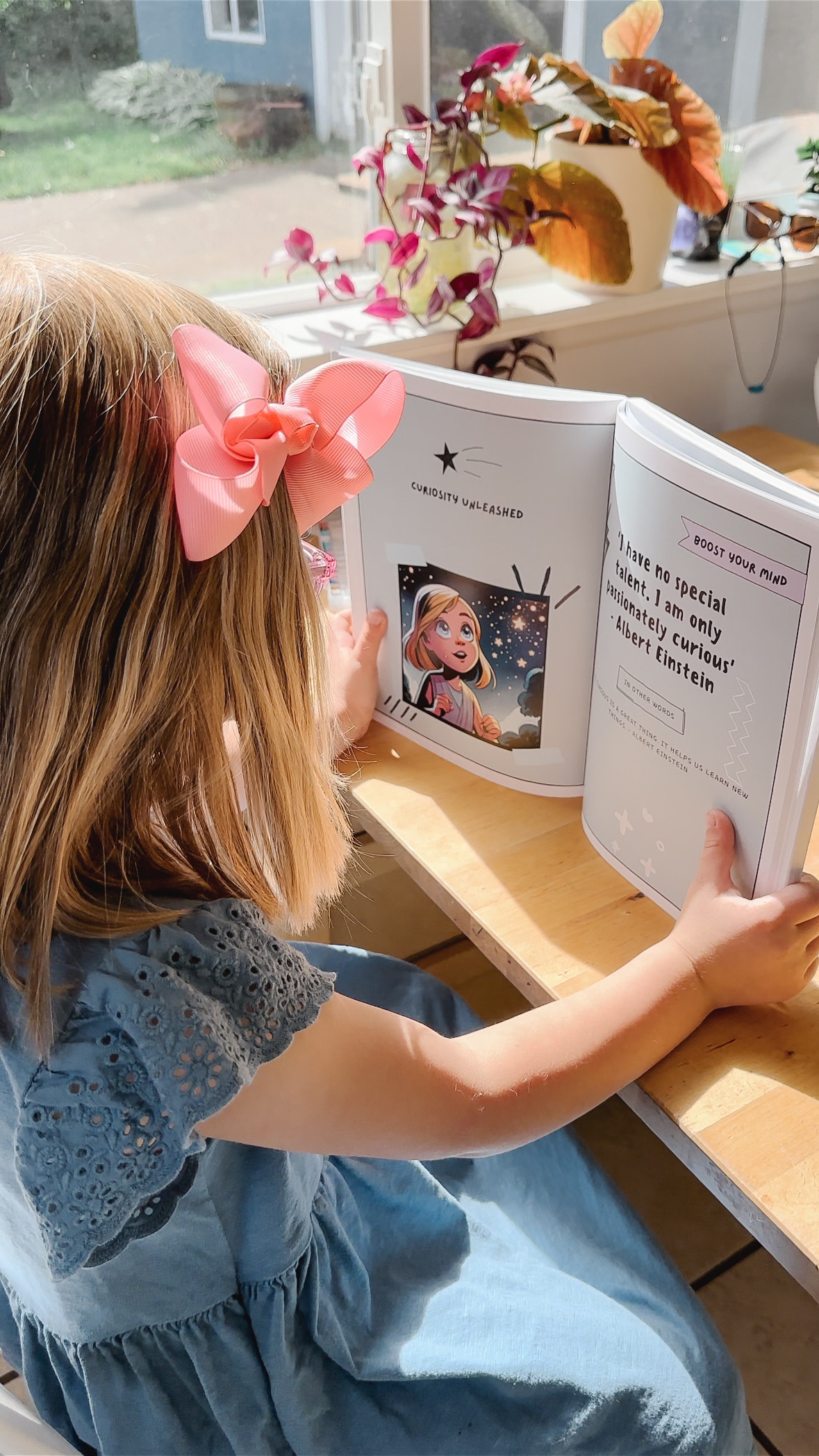 Girl reading personalized book by window — over-the-shoulder showing illustrations